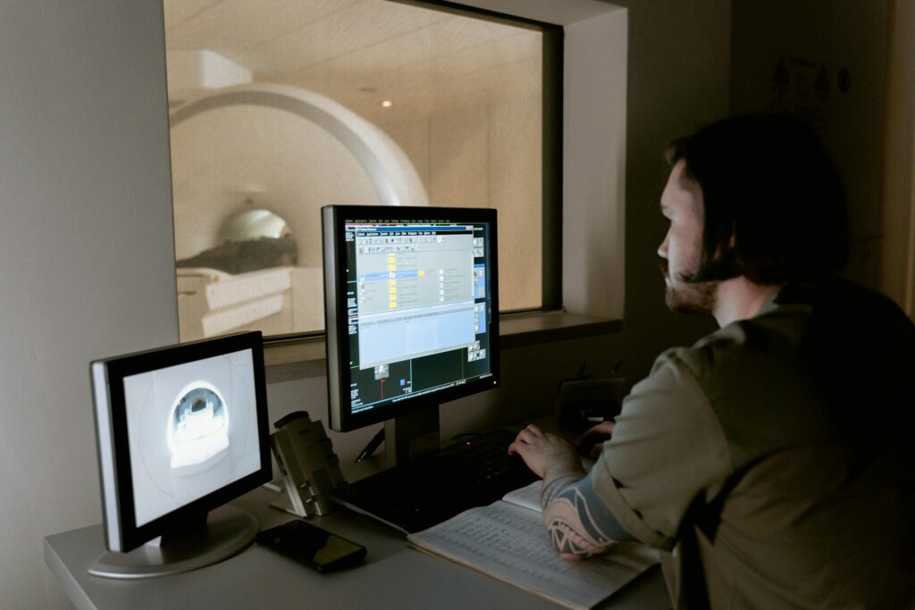A radiologist examines MRI scan results on computer monitors in a medical facility.