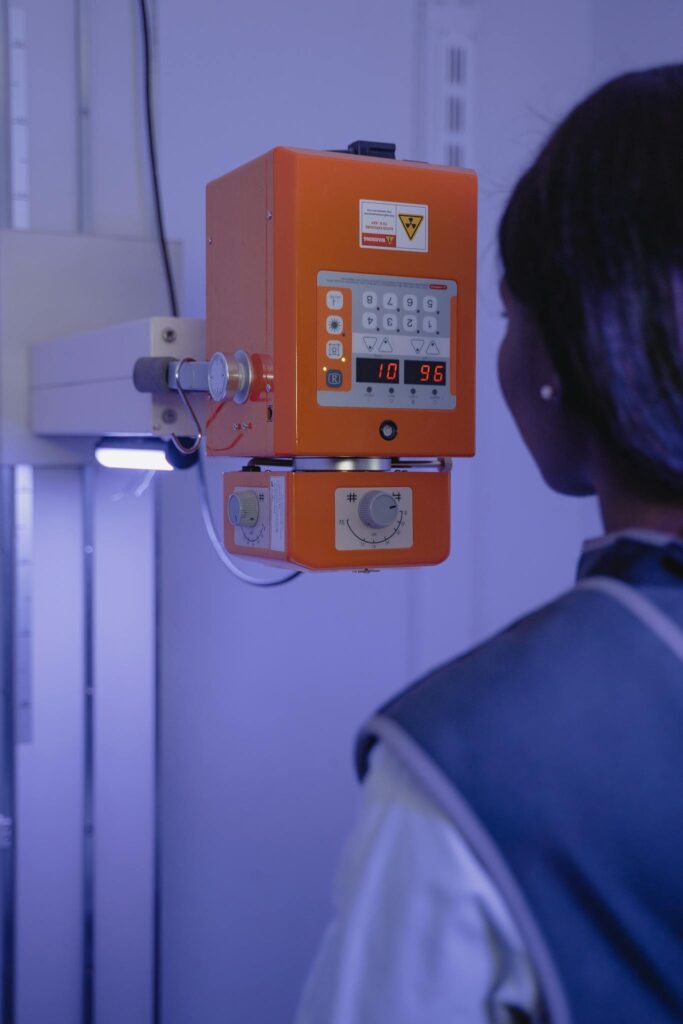 Female radiology technician adjusting settings on an X-ray machine in a medical facility.